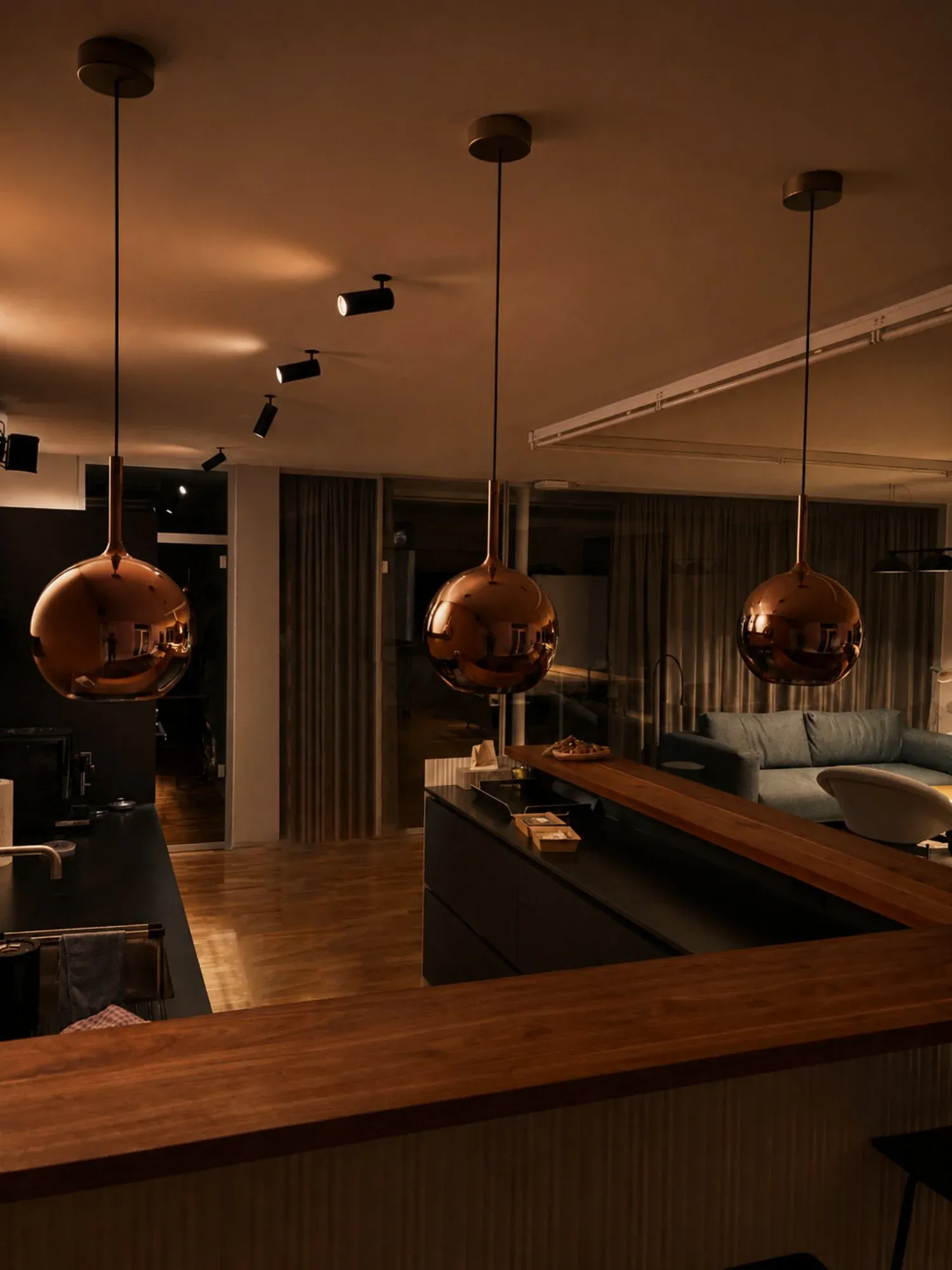 The studio's open kitchen and lounge at night, lit by copper pendant lamps